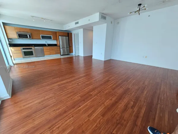 a view of an empty room with wooden floor and a window