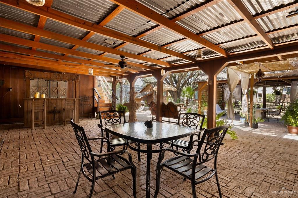 1803 North Bryan Road Mission, TX 78572 - Photo 19 of 30 Covered outdoor patio featuring a corrugated metal roof, exposed wood beams, and a brick-patterned floor