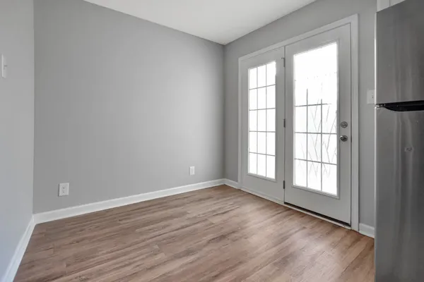 an empty room with wooden floor and windows