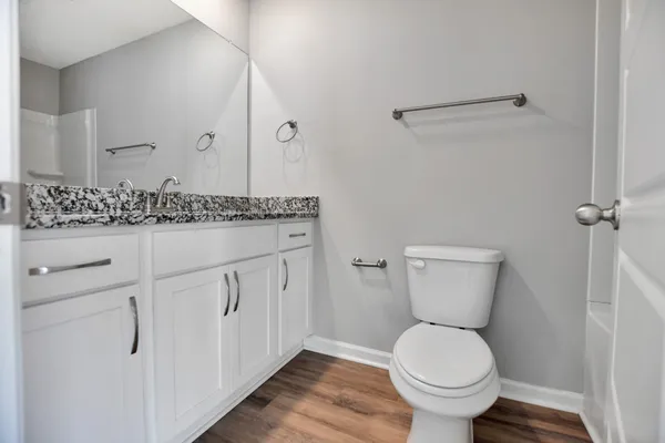 a bathroom with a granite countertop toilet sink and mirror