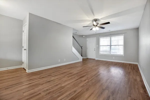 an empty room with wooden floor and ceiling fan