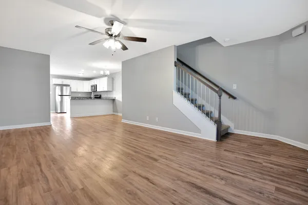 a view of an empty room with wooden floor and a ceiling fan