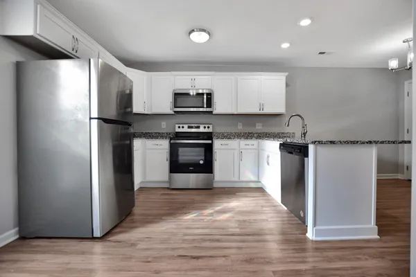 a kitchen with stainless steel appliances granite countertop a refrigerator a sink a stove and oven