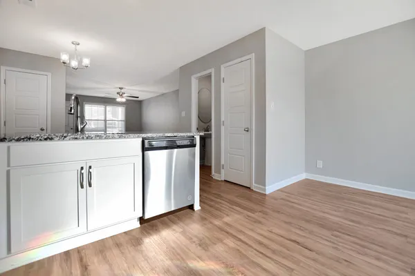 a kitchen with stainless steel appliances granite countertop a refrigerator oven a sink and white cabinets with wooden floor