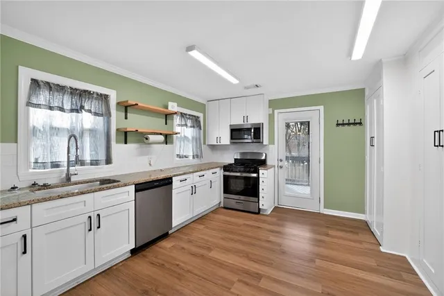 a kitchen with stainless steel appliances granite countertop a refrigerator a sink dishwasher a stove with wooden cabinets and floor