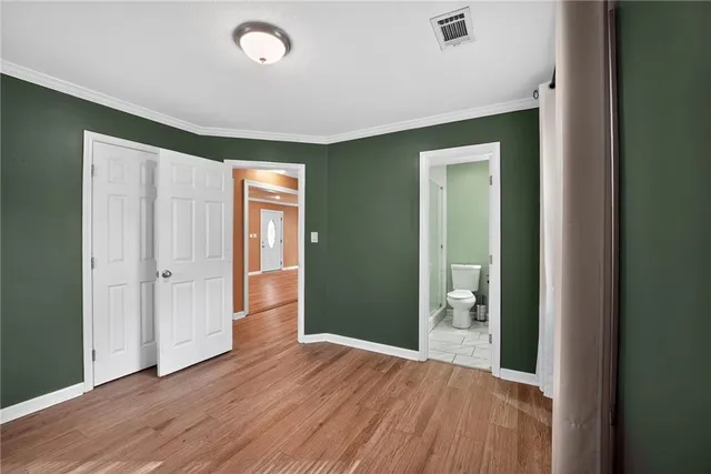 a view of an empty room with wooden floor and closet