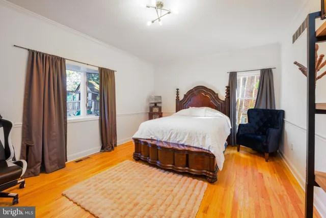 a bedroom with a bed a chair and potted plant on table