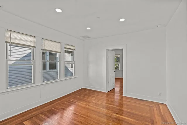 a view of an empty room with wooden floor and windows