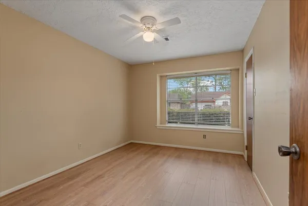 an empty room with a window and a ceiling fan