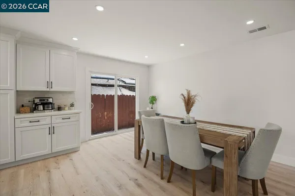 a kitchen with stainless steel appliances a dining table chairs and wooden floor