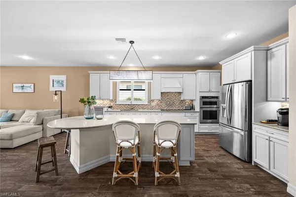 a kitchen with stainless steel appliances a dining table chairs refrigerator and cabinets