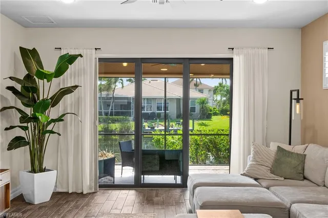 a living room with large windows and plants