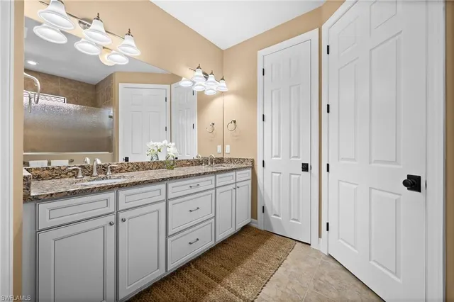 a spacious bathroom with a granite countertop sink a mirror and a shower