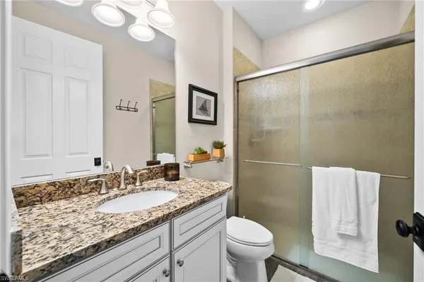 a bathroom with a granite countertop sink toilet and shower