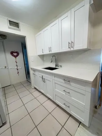 a kitchen with granite countertop white cabinets and a sink