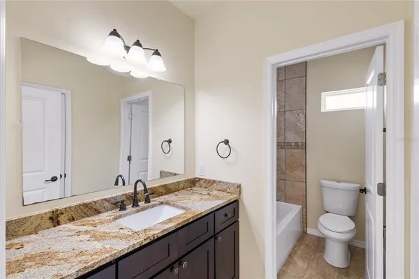 a bathroom with a granite countertop sink toilet and mirror