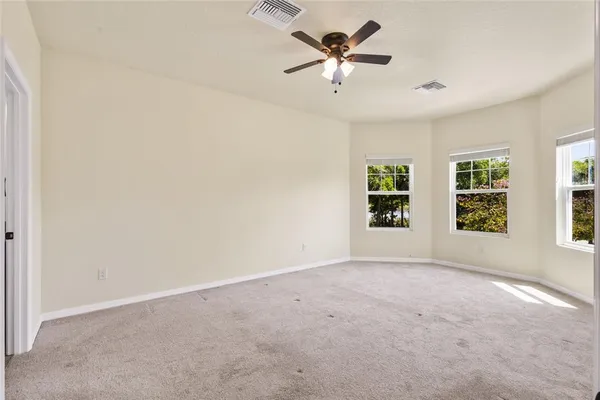 an empty room with windows and chandelier fan