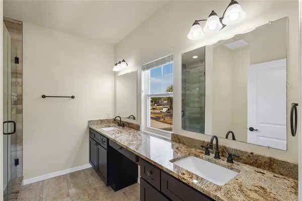 a bathroom with a granite countertop double vanity sink and a mirror
