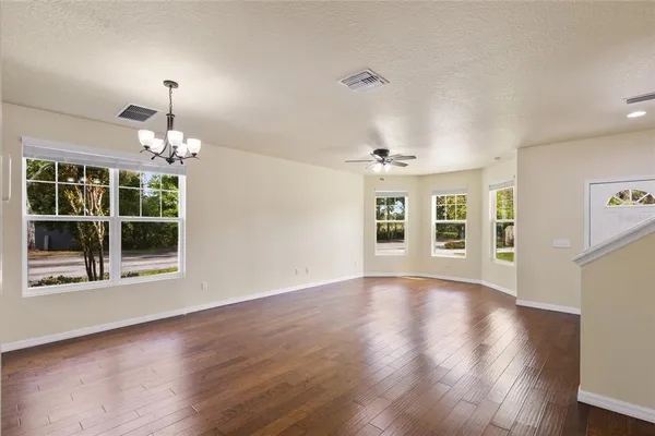 a view of an empty room with wooden floor fireplace and a window