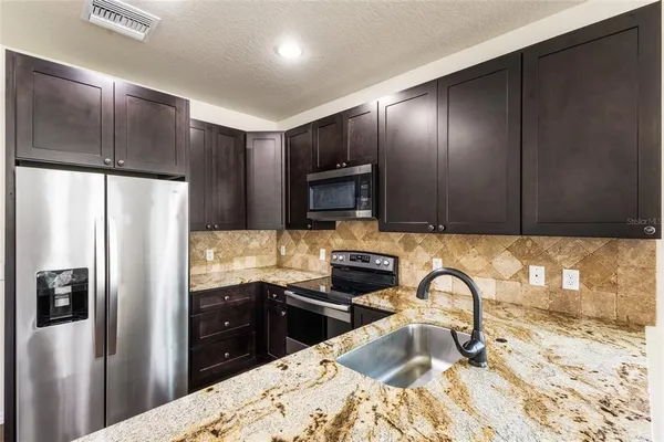 a kitchen with granite countertop stainless steel appliances and refrigerator