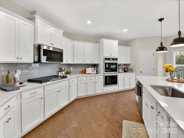 a large kitchen with stainless steel appliances granite countertop a stove a sink and a white cabinets