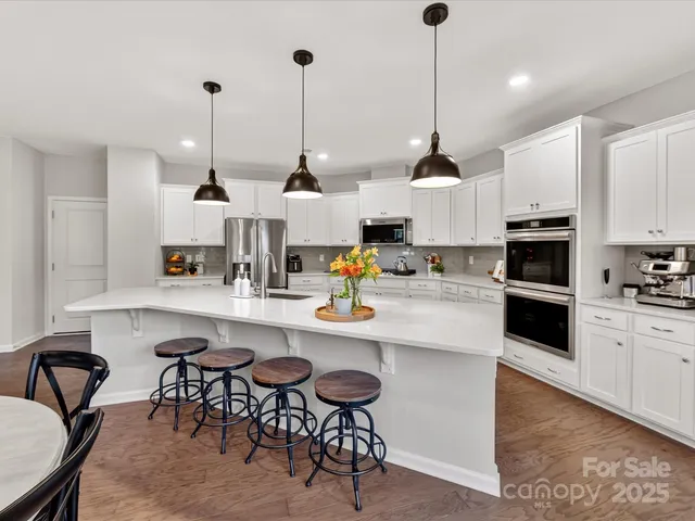 a kitchen with stainless steel appliances kitchen island granite countertop a sink a stove a dining table and chairs