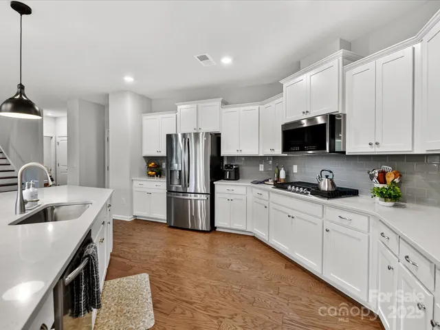 a kitchen with stainless steel appliances a refrigerator sink and white cabinets