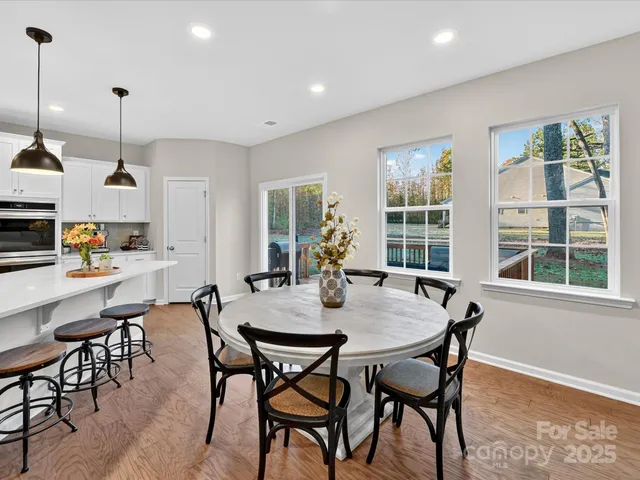 a view of a dining room and livingroom furniture wooden floor a rug and a chandelier