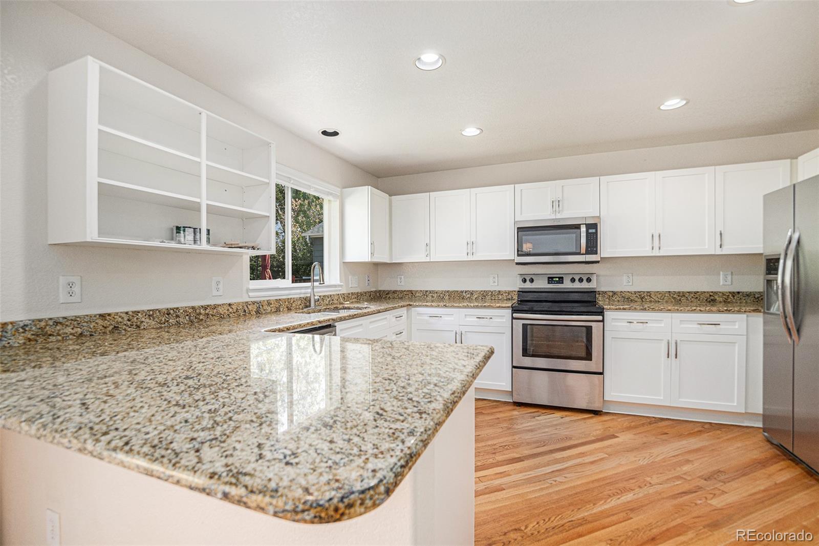 5253 Wangaratta Way Highlands Ranch, CO 80130 - Photo 8 of 43 a kitchen with kitchen island granite countertop a stove a sink and a microwave