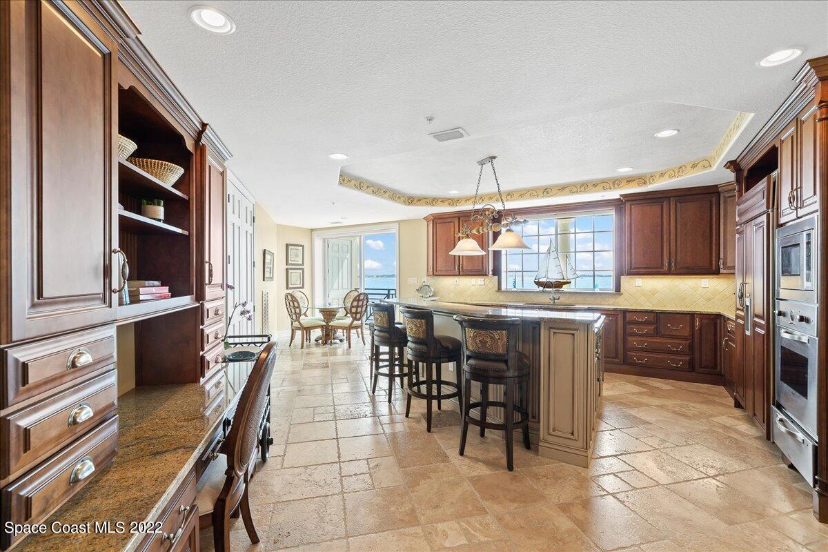 2300 Front Street, Unit 200 Melbourne, FL 32901 - Photo 18 of 92 a kitchen with stainless steel appliances kitchen island granite countertop a table chairs and a refrigerator
