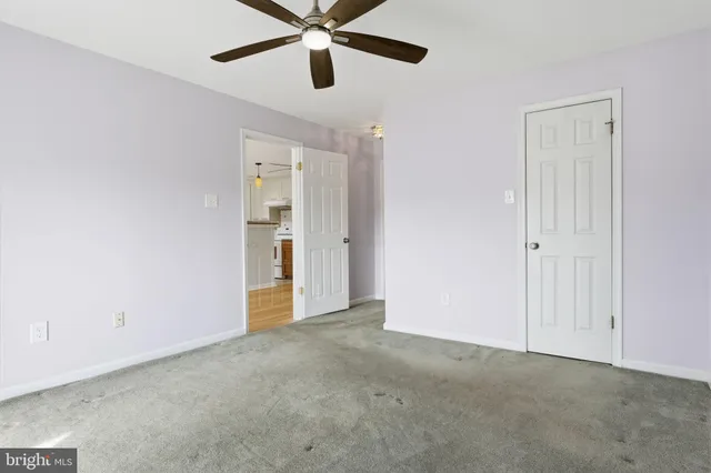 an empty room with closet and a chandelier fan