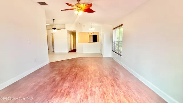 a view of a livingroom with wooden floor and a ceiling fan