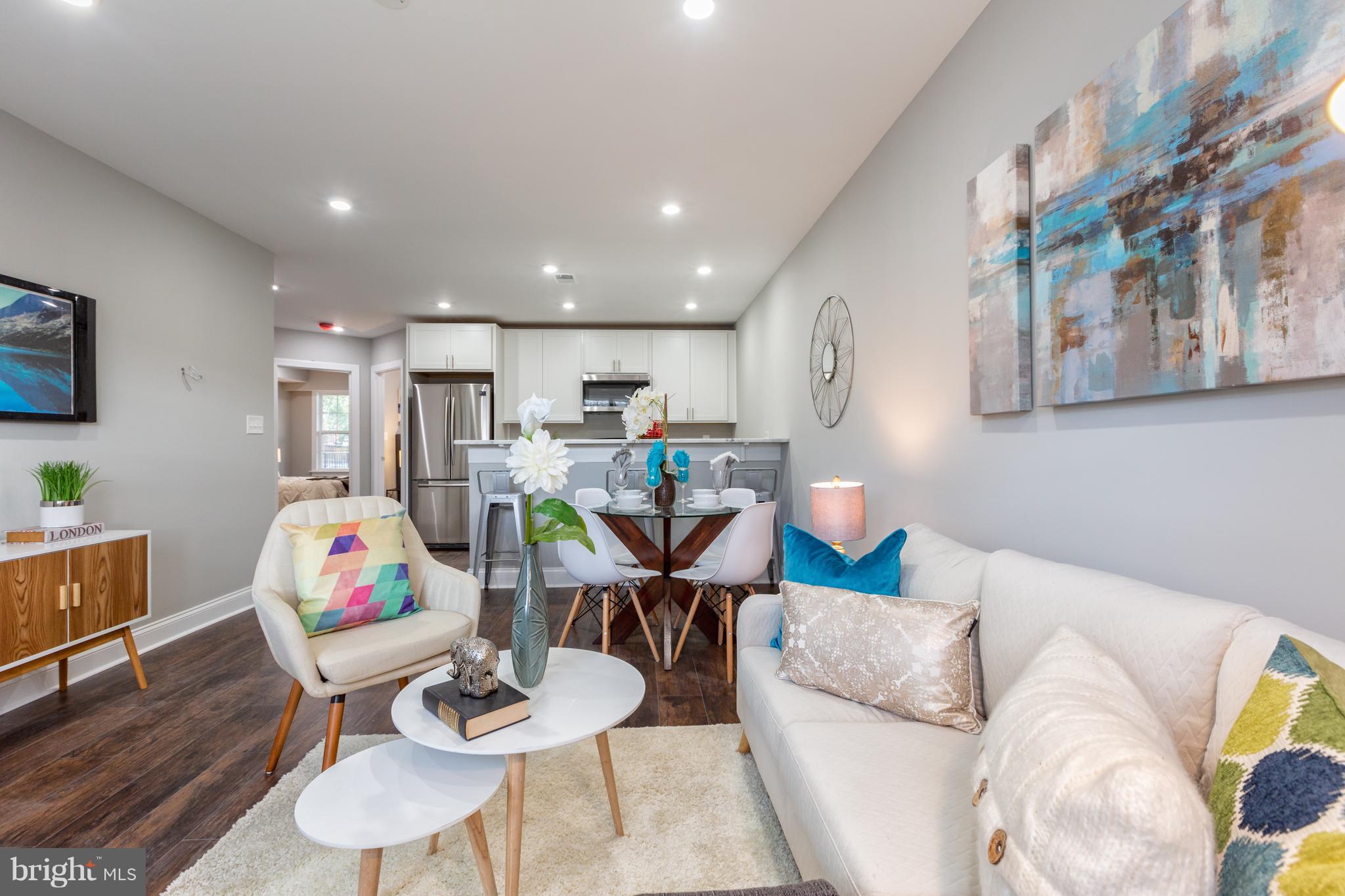 718 Jackson Street Northeast, Unit 1 Washington, DC 20017 - Photo 2 of 26 a living room with furniture and a dining table with wooden floor