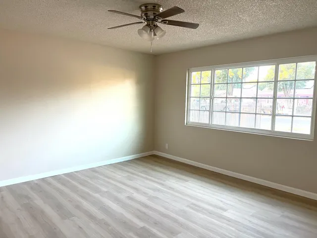 an empty room with windows and fan