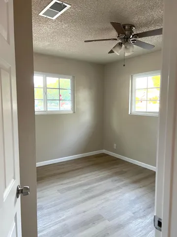 an empty room with a window and a ceiling fan