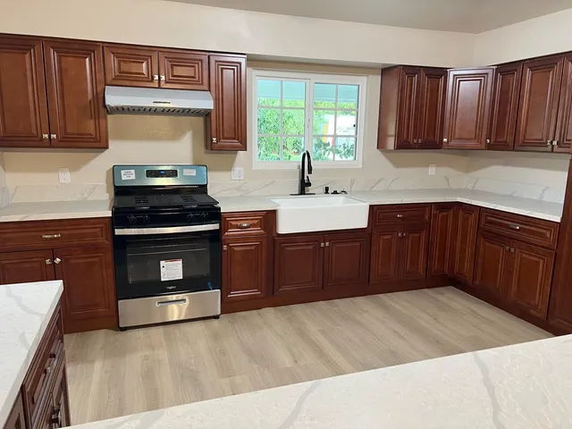 a kitchen with stainless steel appliances granite countertop wooden cabinets a stove top oven a sink and dishwasher