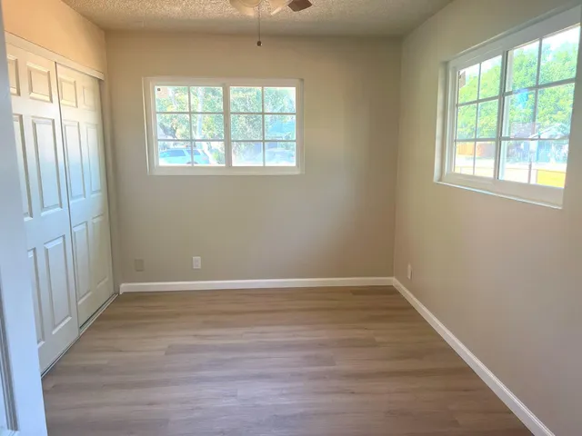 an empty room with wooden floor and windows