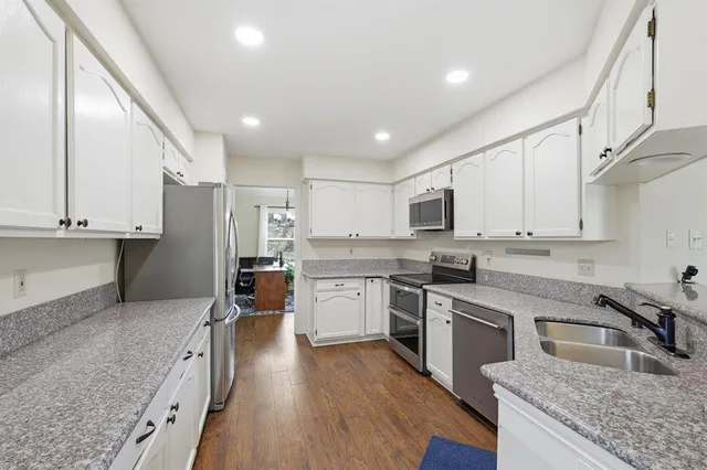 a kitchen with granite countertop stainless steel appliances refrigerator sink and cabinets