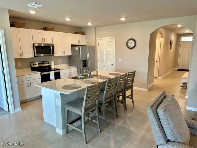 a kitchen with stainless steel appliances a dining table chairs refrigerator and microwave