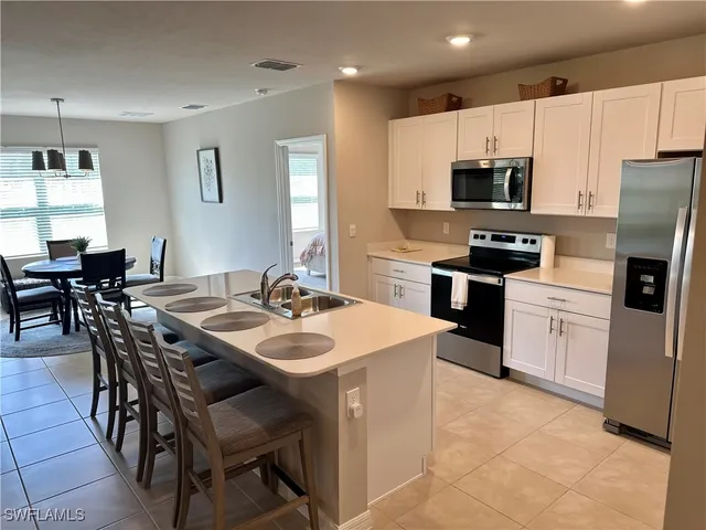 a kitchen with stainless steel appliances a white table chairs and a refrigerator