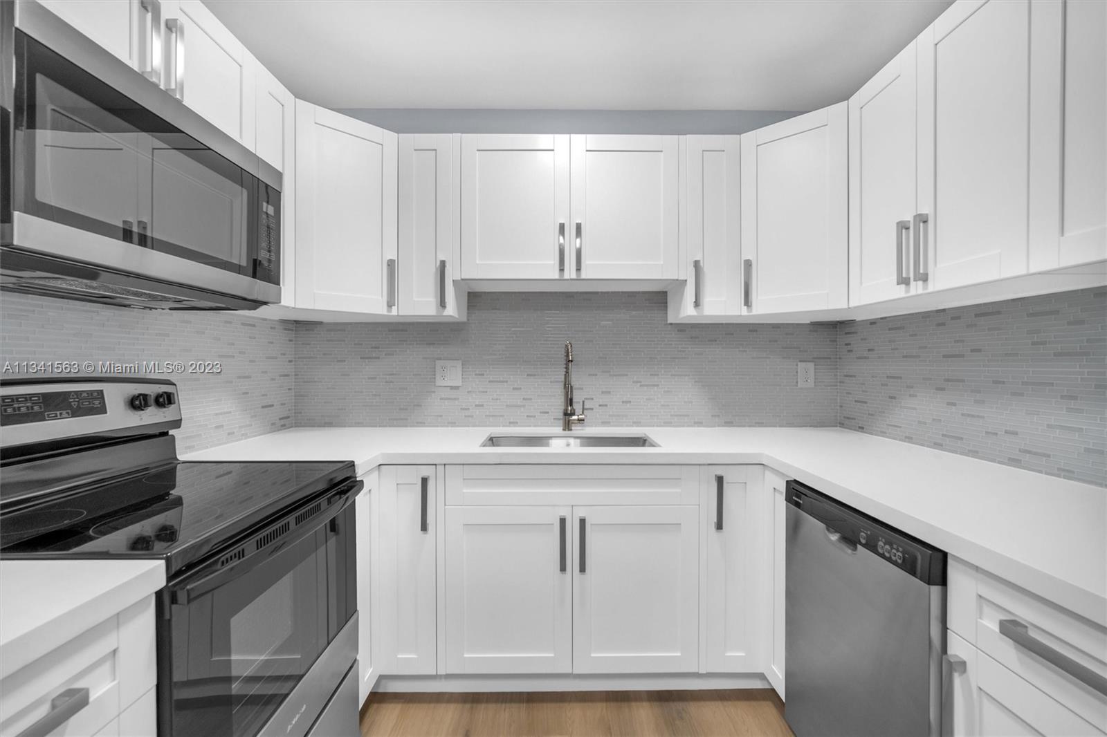 217 East 24th Street Riviera Beach, FL 33404 - Photo 3 of 27 a kitchen with white cabinets stainless steel appliances and sink
