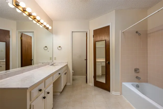 a spacious bathroom with a tub sink and mirror