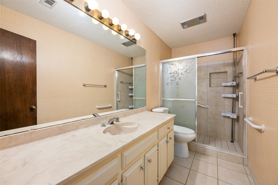 9424 El Rey Boulevard Austin, TX 78737 - Photo 21 of 35 a bathroom with a sink a toilet a mirror and shower