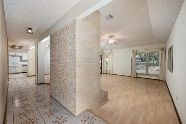 an empty room with fireplace chandelier and windows