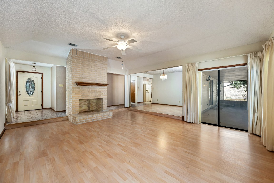 9424 El Rey Boulevard Austin, TX 78737 - Photo 5 of 35 an empty room with fireplace chandelier and windows