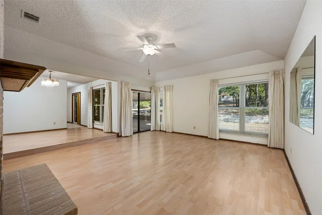 a view of an empty room with wooden floor and a fireplace