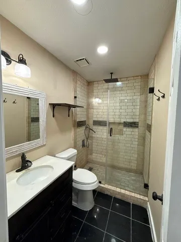 a bathroom with a sink a toilet a mirror and shower