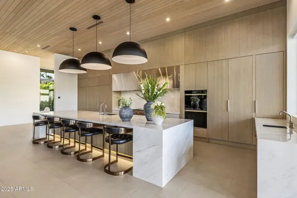 a kitchen with kitchen island stainless steel appliances a dining table a sink and a refrigerator