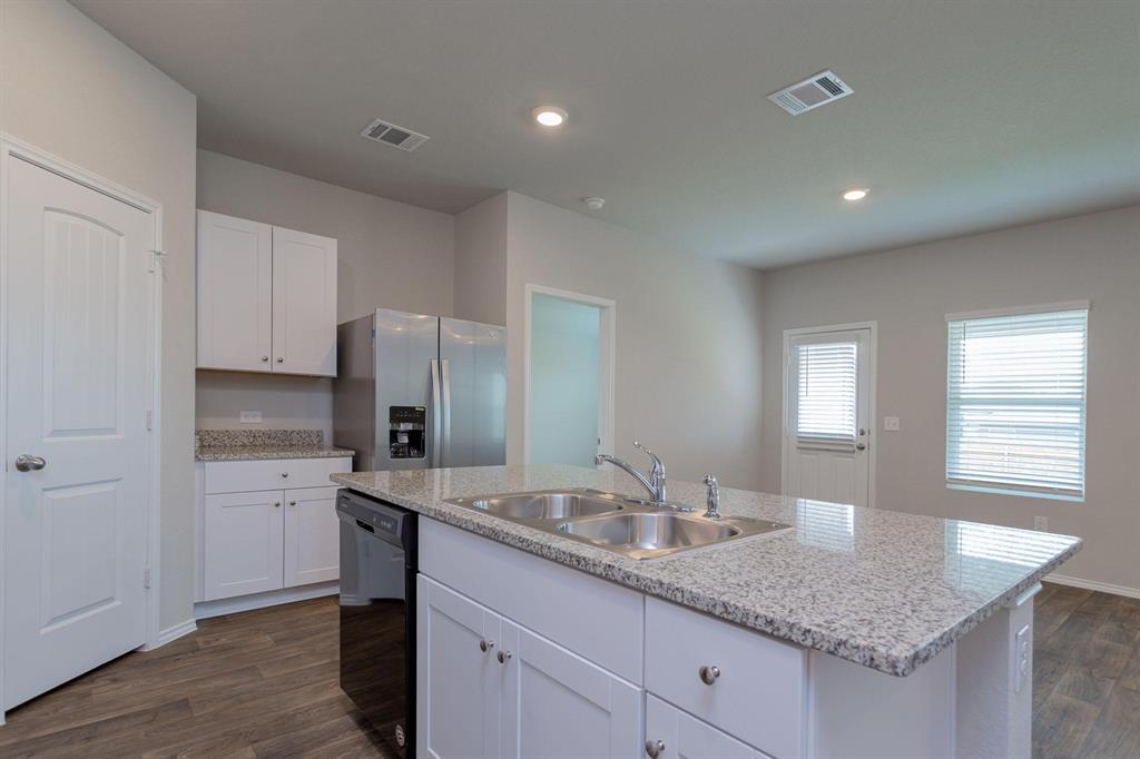 6009 Ronee Leah Drive Austin, TX 78724 - Photo 5 of 16 A clean, modern kitchen features an island with a double sink and ample granite counter space.