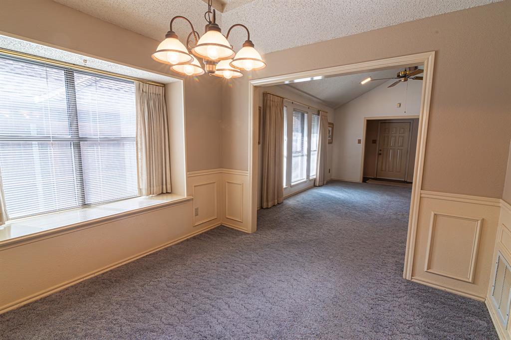 2028 Falcon Ridge Drive, Unit B Carrollton, TX 75010 - Photo 5 of 11 Empty room featuring suspended lighting, carpet, a decorative wall, ceiling fan, and wainscoting